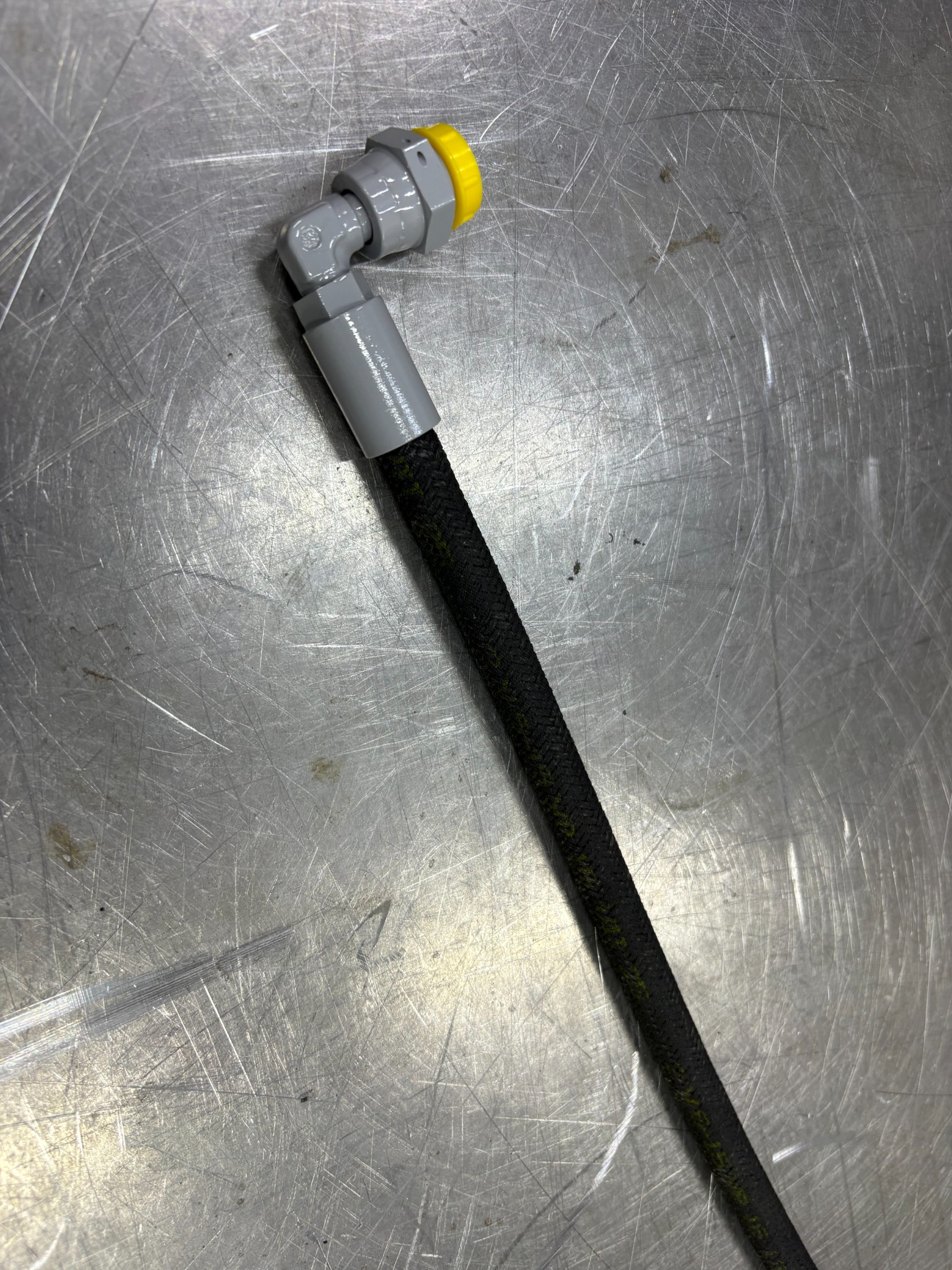 Rubber hose with a grey elbow fitting and yellow protective cap