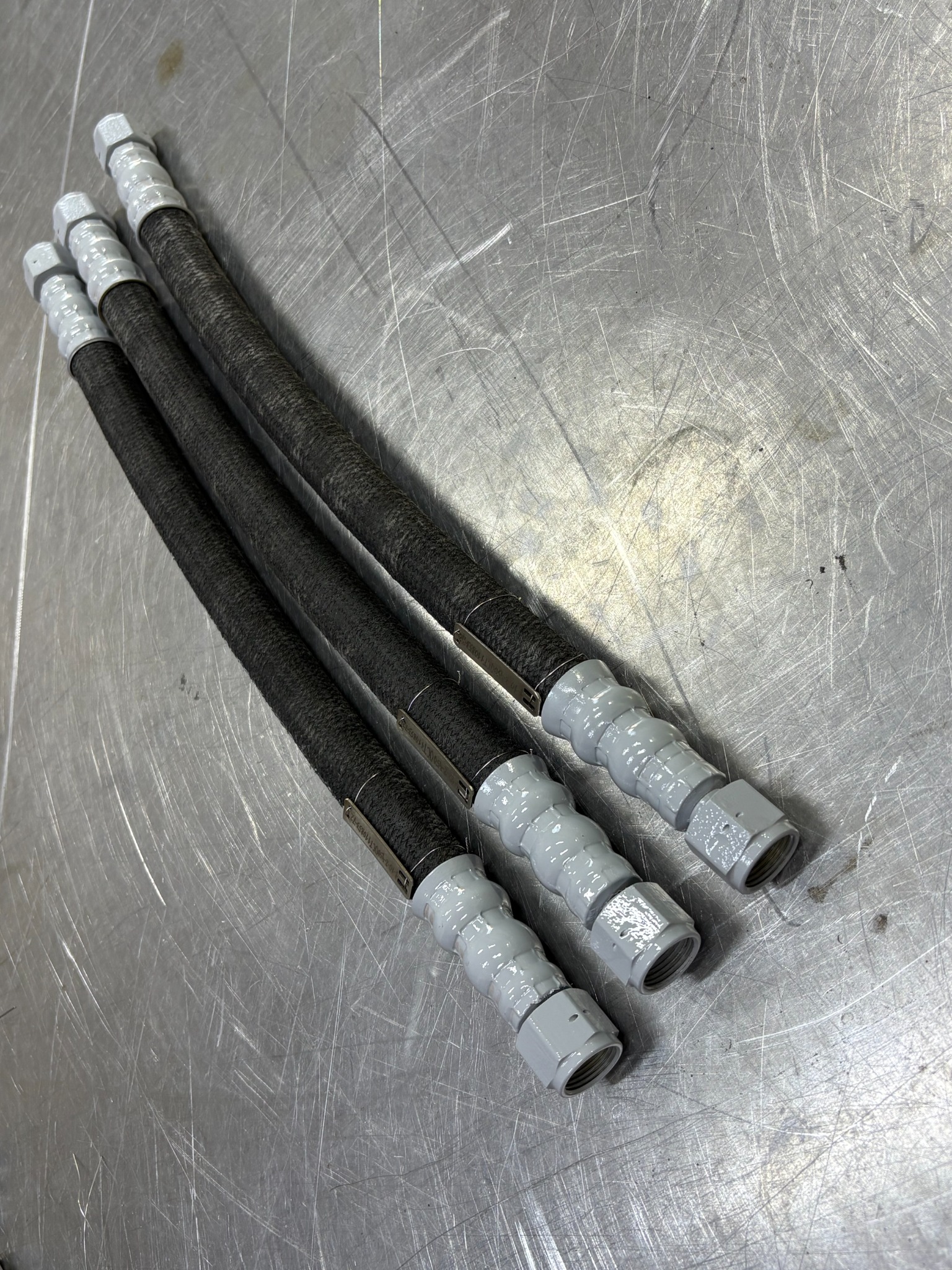 Close view of three rubber hose assemblies and straight end fittings